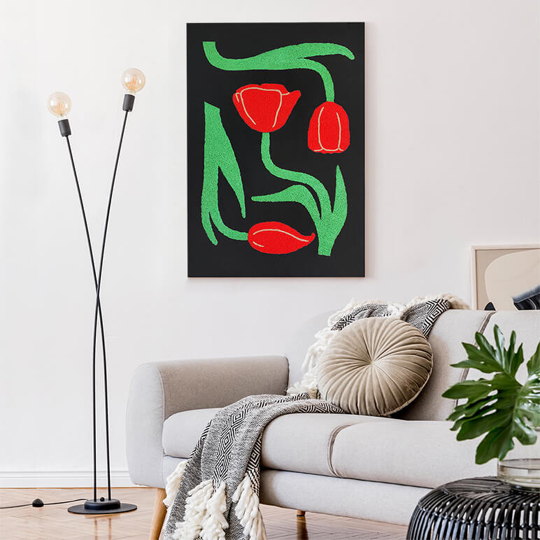 Mood shot of an embroidered textile artwork in black, red and green colours of tulips, seen displayed in a modern white living room