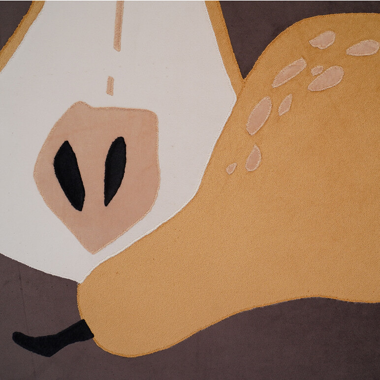 Embroidery detail seen close up to show the patchwork in earthy colors of mustard, cream, black and brown