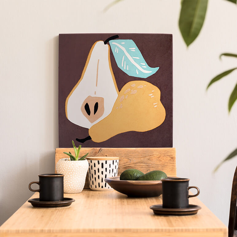 Canvas framed food themed wall art in earthy brown and mustard colors featuring a half cut pear