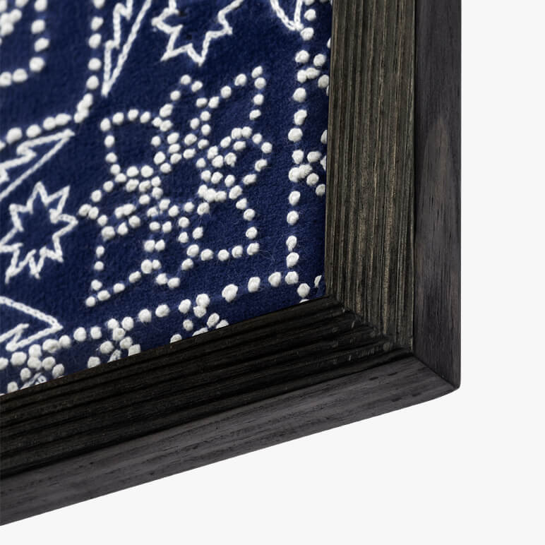 angled corner detail of a fire crafted shou sugi ban frame in black with a blue tapestry framed inside