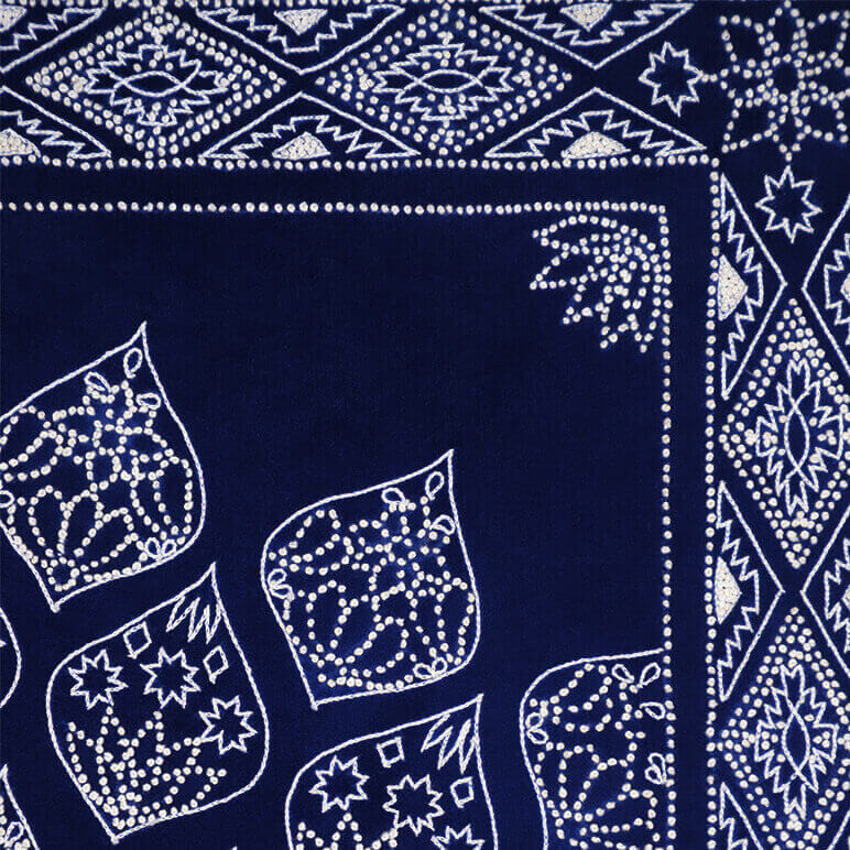 embroidery detail in white over a blue suede background 