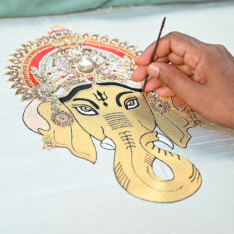 Detailed view of the embroidery of a Ganesha textile artwork, being handcrafted by an artisan