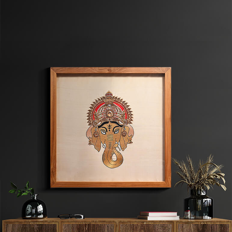 Lifestyle shot of a Ganesha artwork, framed in wood and displayed on a dark wall over a wooden console table