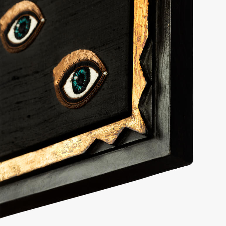 corner detail of a framed glam wall décor piece featuring sequined blue eyes