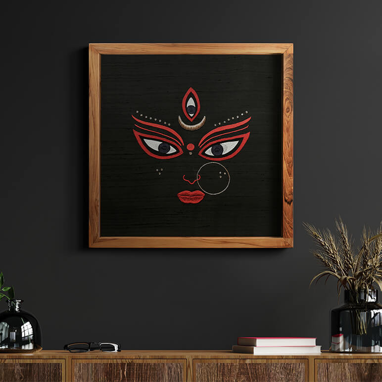 Staged image of a Goddess Durga artwork seen displayed over a dark wall behind a wooden console table