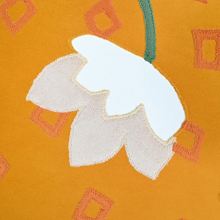 Detailed close up view of the patchwork done in orange, green, cream and and white on a textile artwork