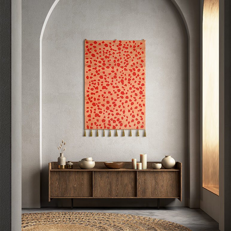 handcrafted jewel toned tapestry in pink and red seen hanging on a grey wall in a modern foyer