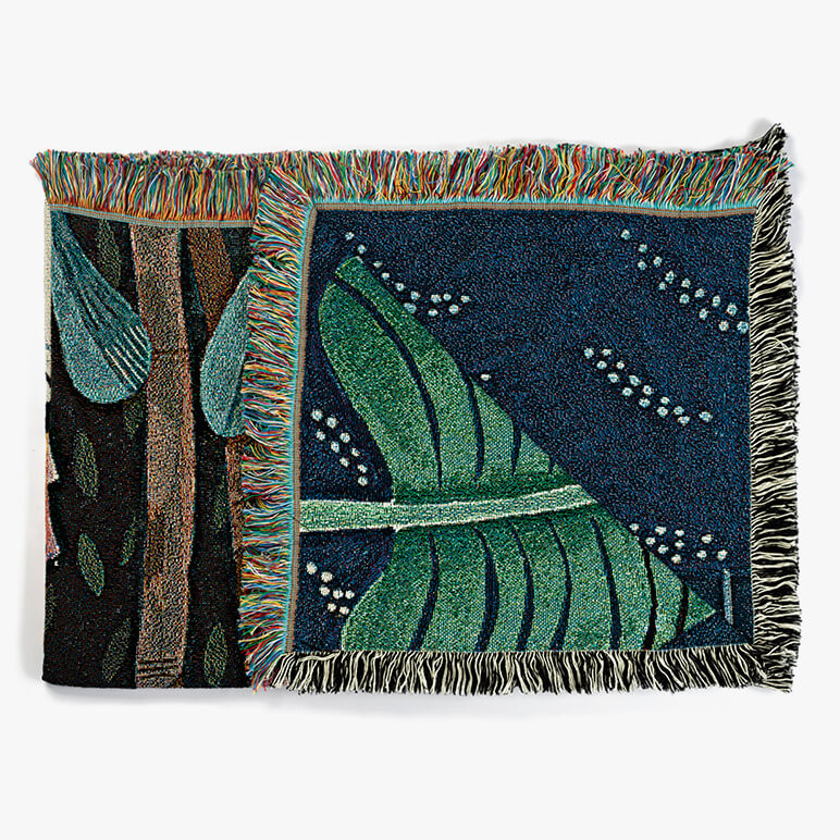 folded throw blanket showing jungle foliage and multicolored tassels