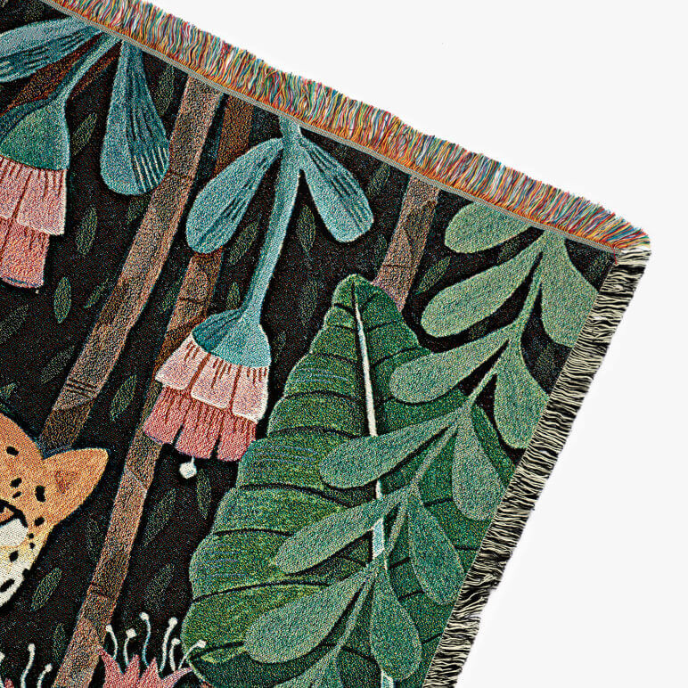 corner of a woven throw showing a part of a cheetah amidst jungle foliage and flowers