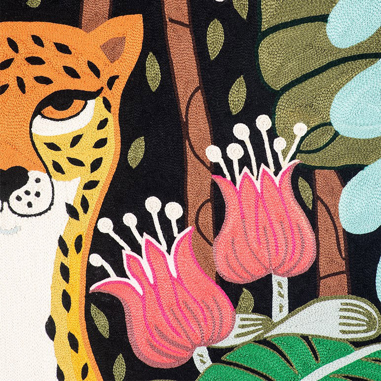 embroidery detail showing forest foliage and half a cheetah's face
