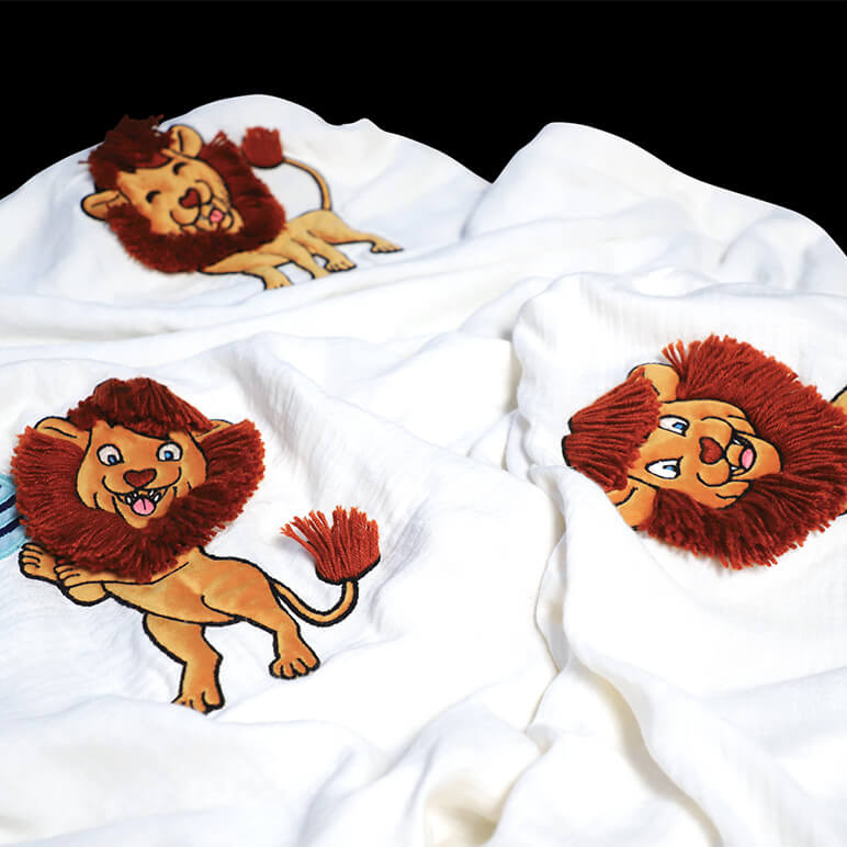 cute lion throw blanket with multiple embroidered lions over a bamboo cotton fabric background in white