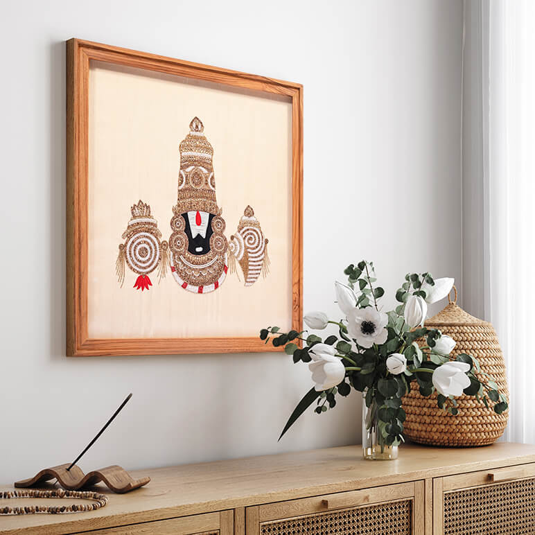 Staged view of Lord Venkateswara textile artwork, framed in wood, displayed over a white wall in an organic modern room