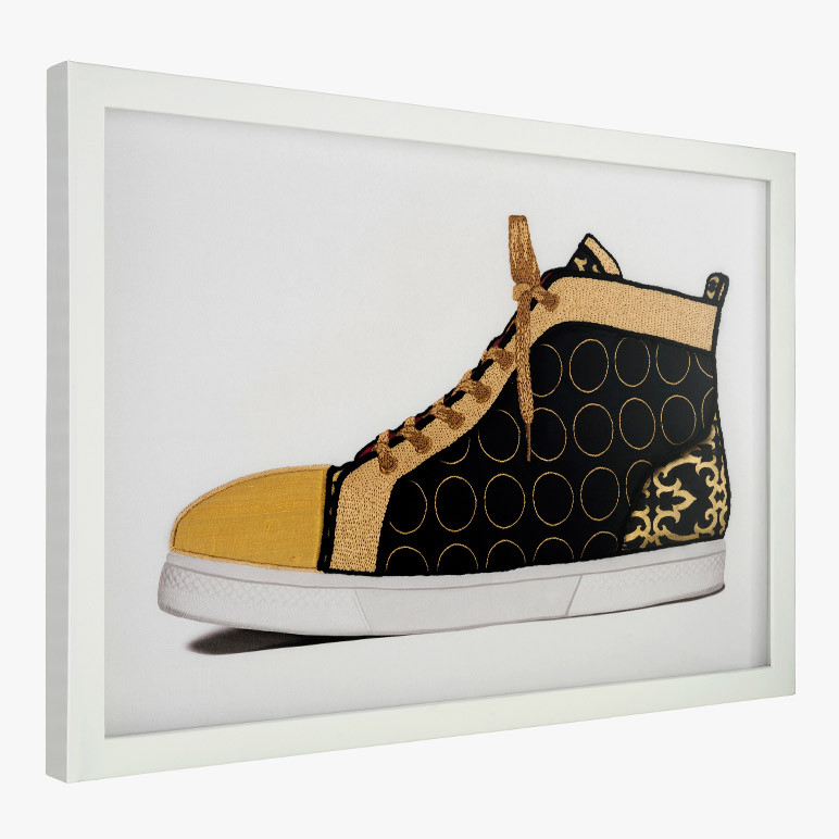 side angle view of a framed black and gold sneaker