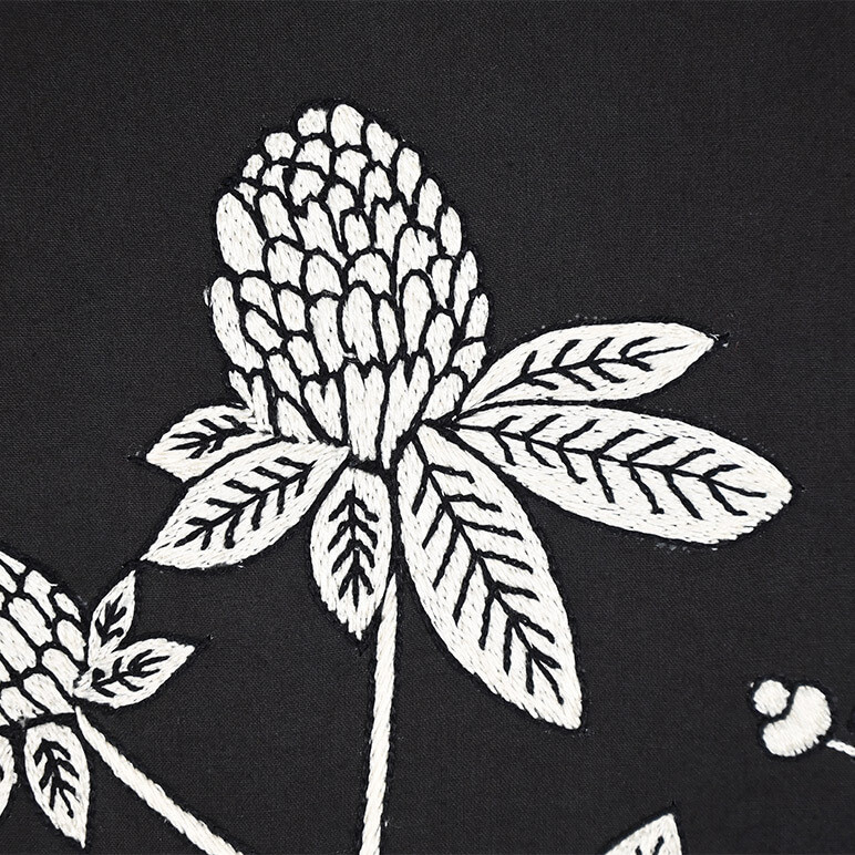 Close up view of the embroidery detail on a minimalist wall art with wildflowers, in black and white colors