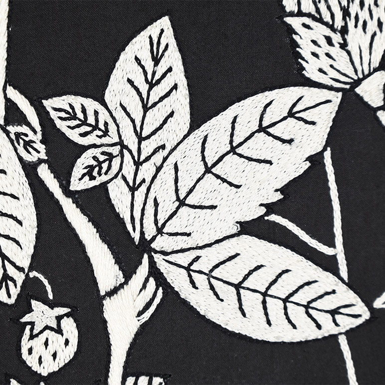 Detail view of the embroidery in white over a black cotton background