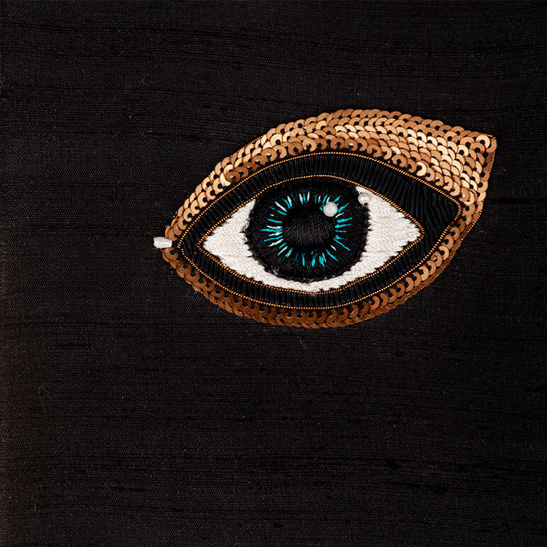 close-up view of an embroidered blue eye over a black silk background