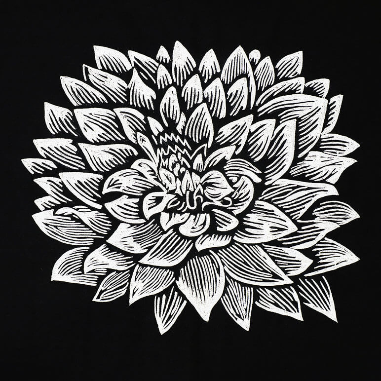 close-up view showing the embroidery detail of a white dahlia flower over a black cotton background