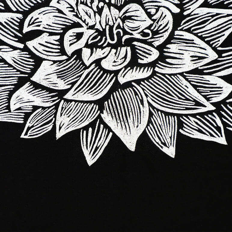 close-up view showing the embroidery details of a white dahlia flower over a black cotton background