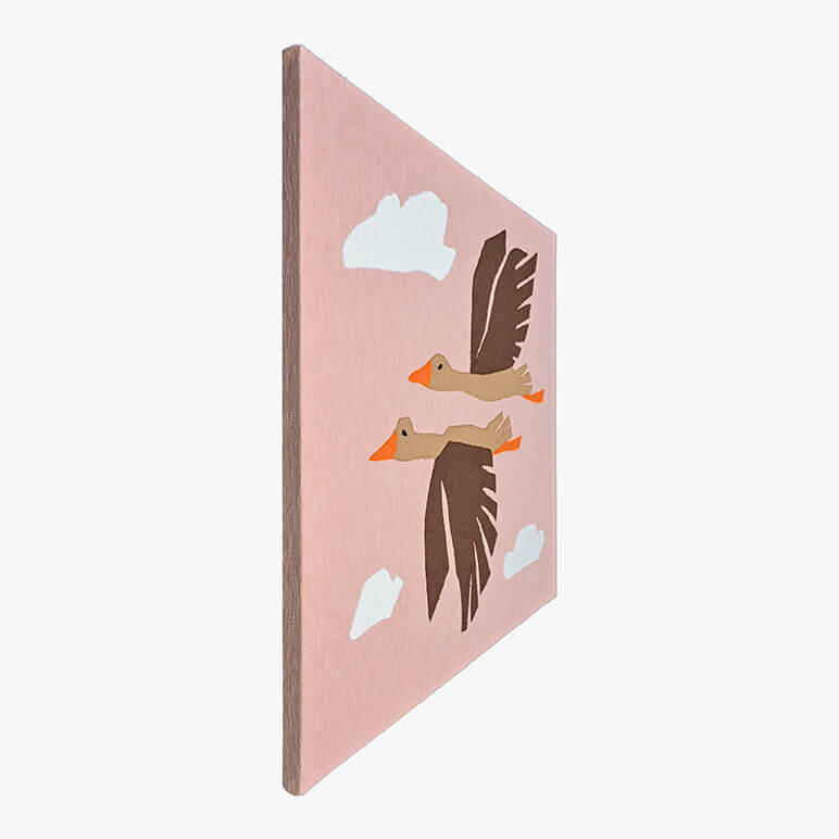 Left angle view of a canvas framed patchworked textile art with flying birds amidst a pink sky and white clouds