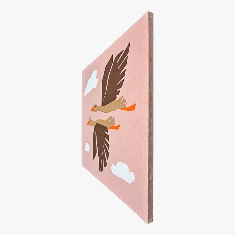 Right angle view of a canvas framed patchworked textile art with flying birds amidst a pink sky and white clouds