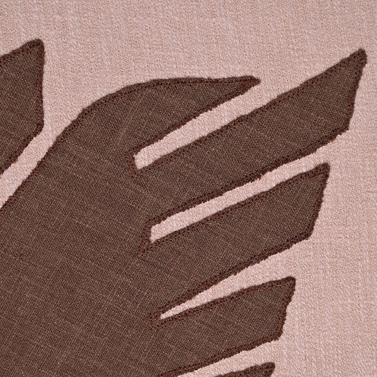 Close up view of the patchworked embroidery detail in brown and pink cotton