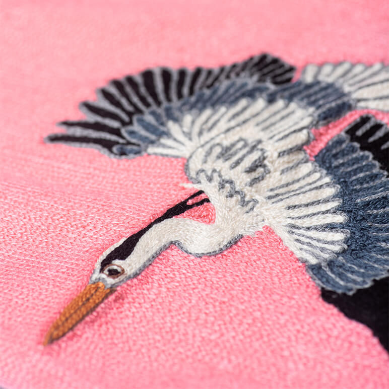 close-up view of an embroidered pink nursery wall art tapestry with a white heron