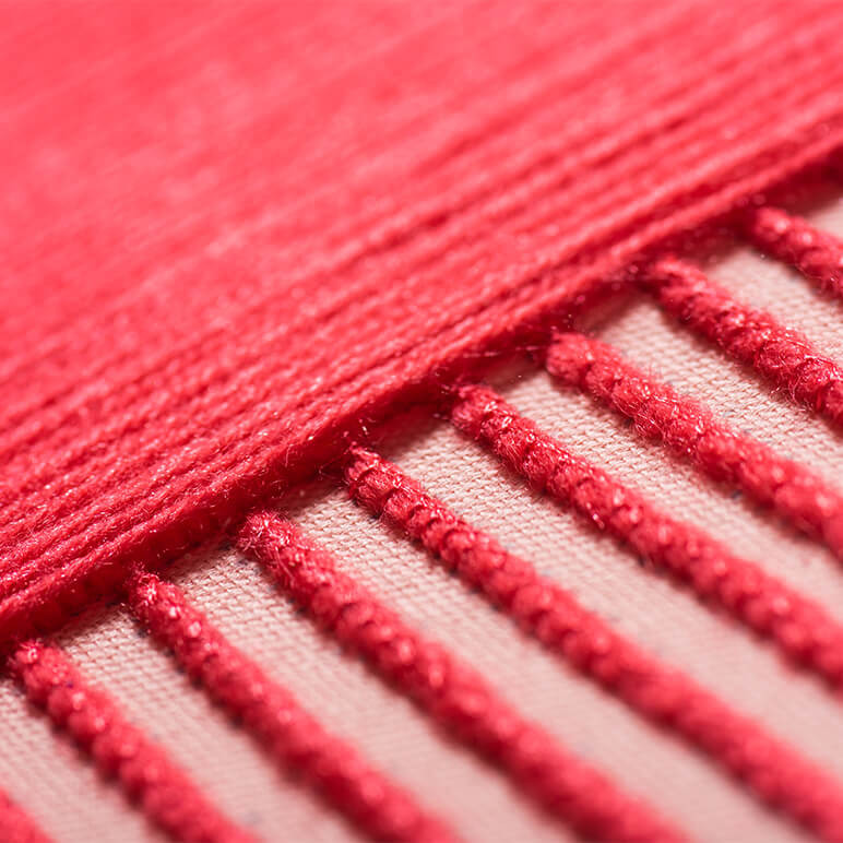 closeup of embroidery in pink wool in a textile wall artwork