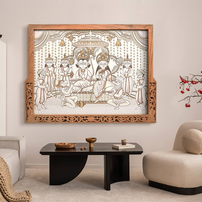 Styled image of Ram Darbar textile artwork seen displayed in a carved wooden frame in a neutral colored living room