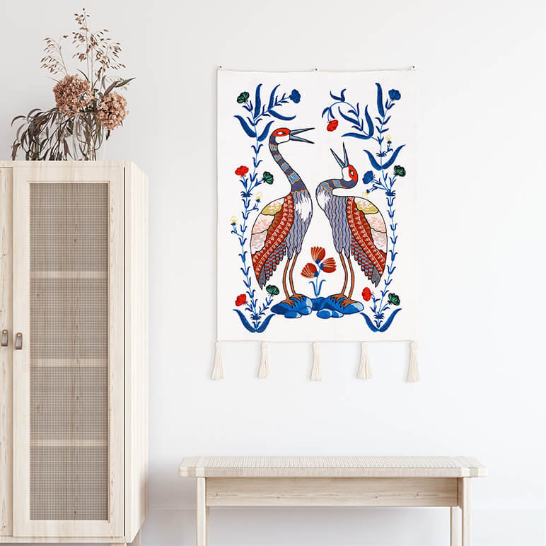 blue and white wall hanging with a woolen embroidered pair of Sandhill cranes and macramé tassels