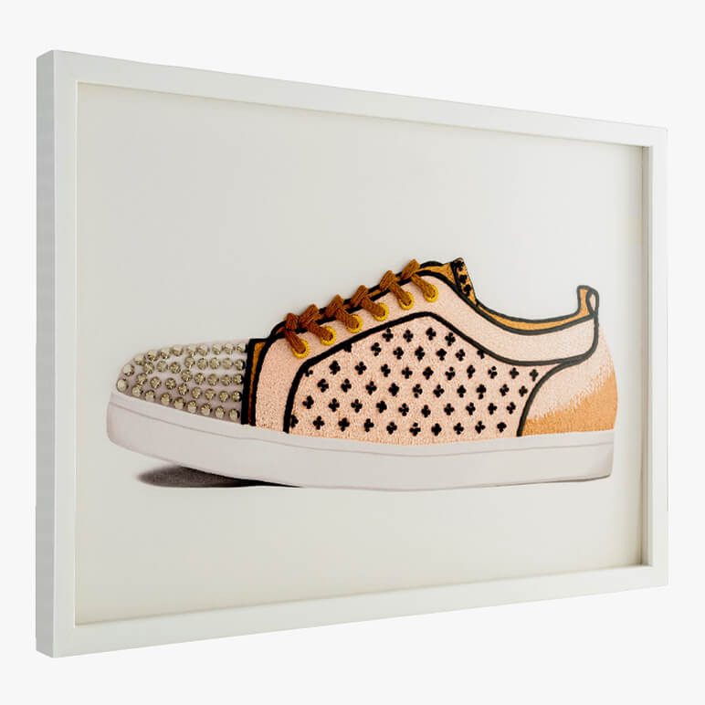 side angle view of a framed shoe wall artwork featuring a nude and brown colored hand-embroidered sneaker