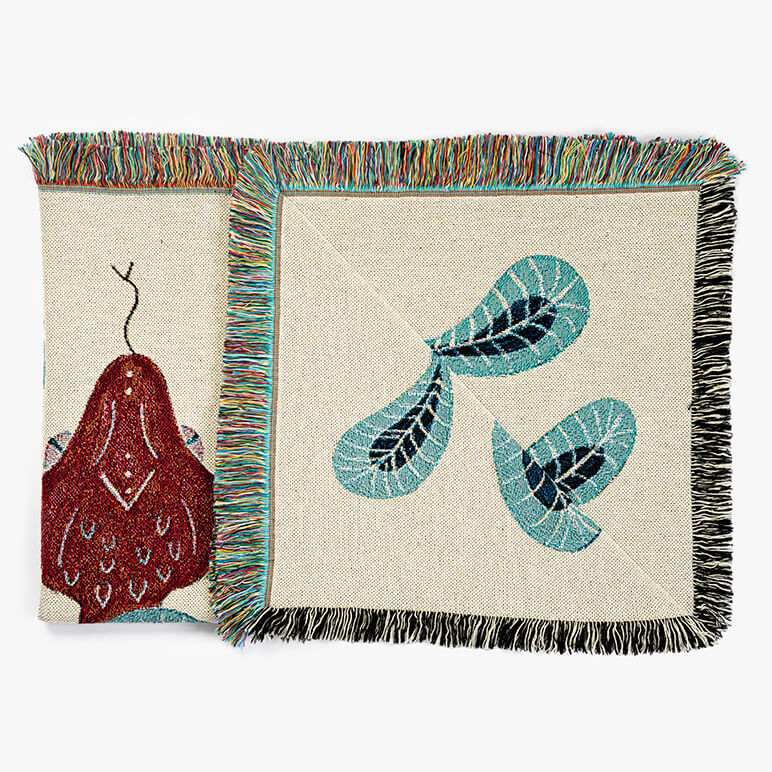 folded throw blanket showing a red snake head and teal colored foliage