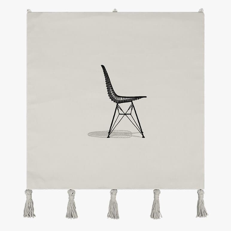 modern still life tapestry in beige color with a hand-embroidered Eames chair at the center and hanging macramé tassels at the bottom