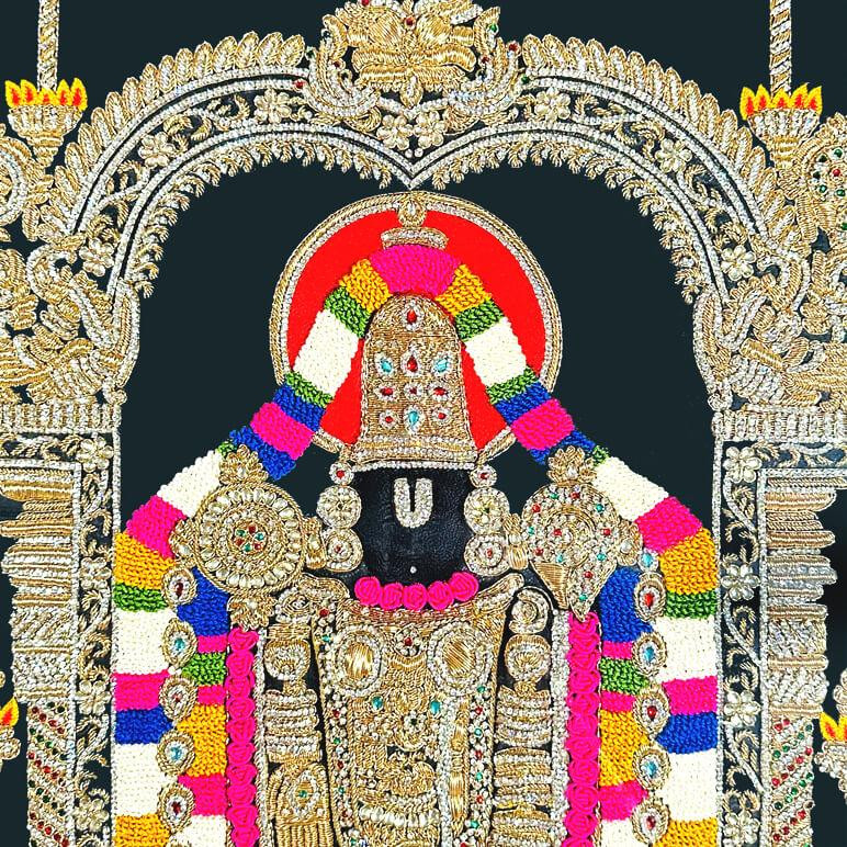 Embroidery detail seen in close up with vibrant colours like gold, white, red, yellow, green and silver over a black fabric background