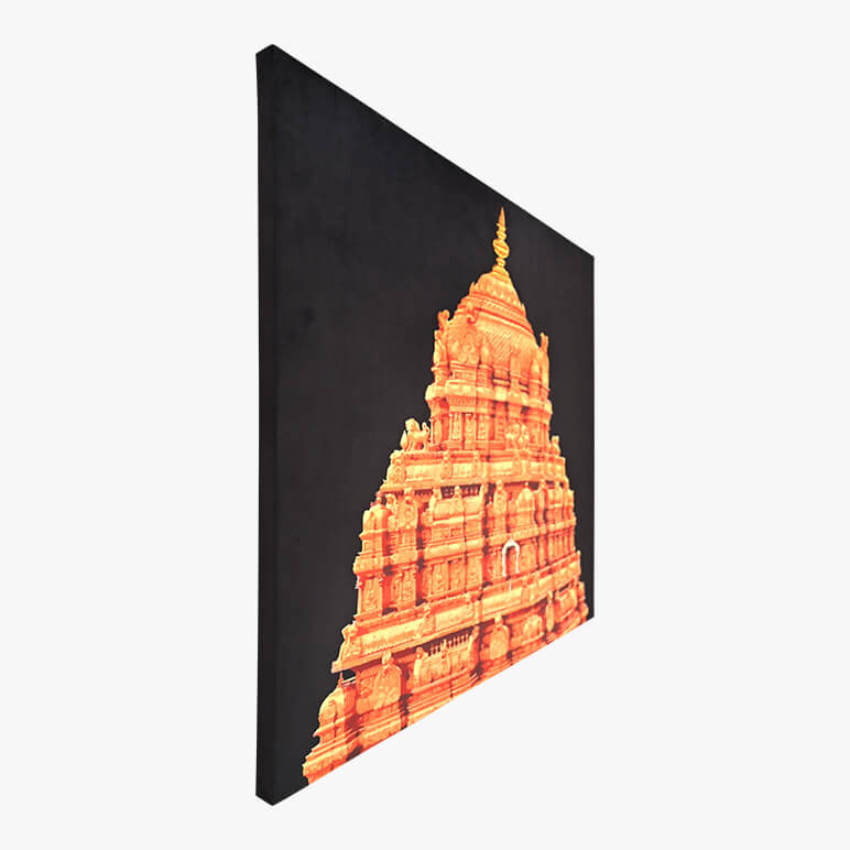 Image showcasing a textile artwork from the left angle. The artwork showcases the Tirupati Balaji Temple in gold over a deep black fabric background. It is canvas framed.