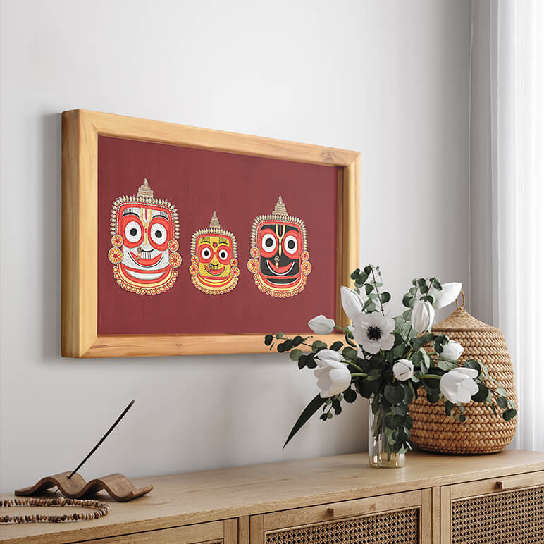 Staged view of a textile art featuring the holy trio of Lord Jagannath, Balaram and Subhadra displayed over a wooden console table