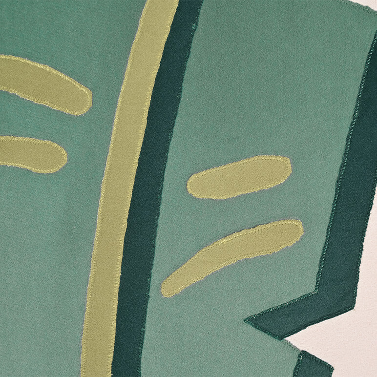 Embroidery close up view showing the patchwork done on a tropical textile wall art, in green color tones