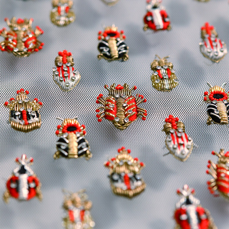 closeup of embroidered insects in red, gold, black and silver