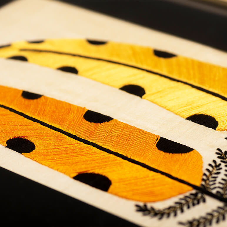 modern folk embroidery featuring a pair of yellow polka dotted feathers