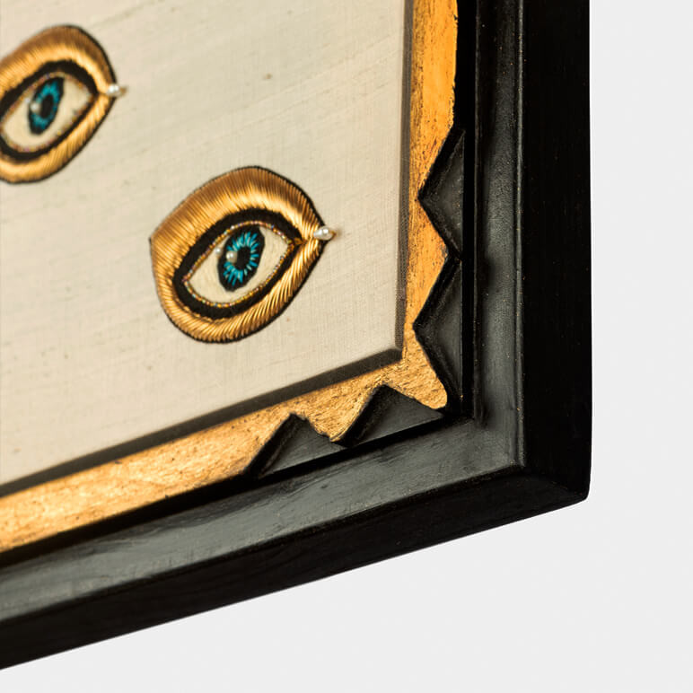 frame corner detail showing the black and gold colored frame holding a textile artwork