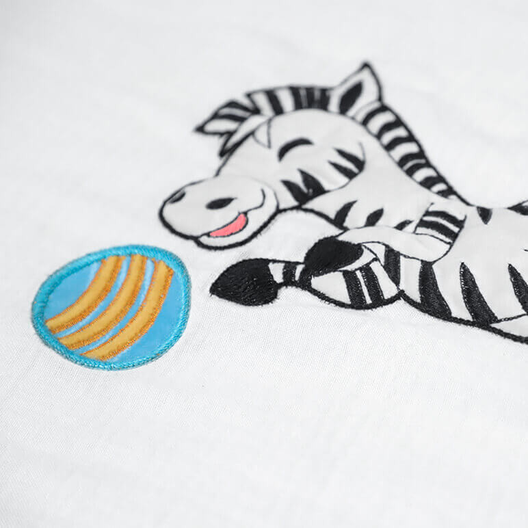 bamboo cotton background with an embroidered black and white zebra playing with a blue ball