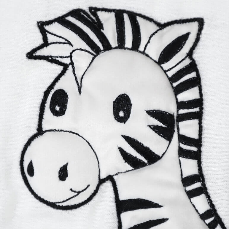 closeup view of an embroidered zebra head in black and white over a bamboo white cotton fabric background